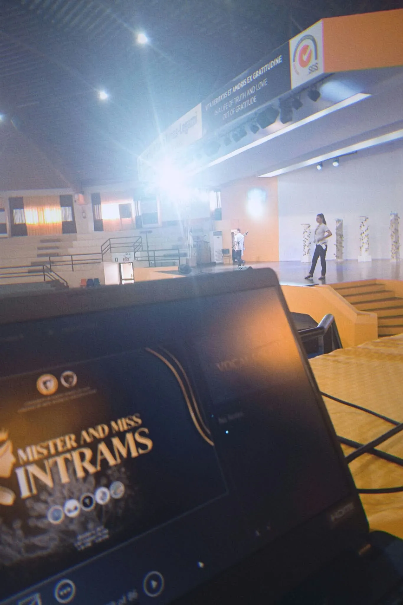 A laptop showing the Mister and Miss Intrams title card, the stage beyond.