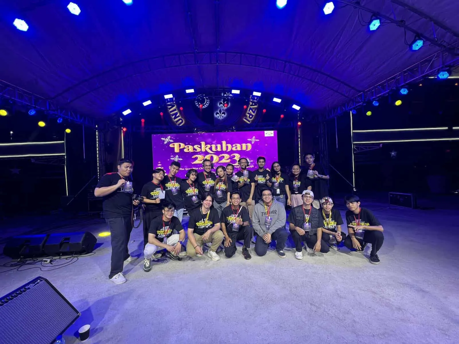 The Paskuhan crew posing on the stage under blue lights.