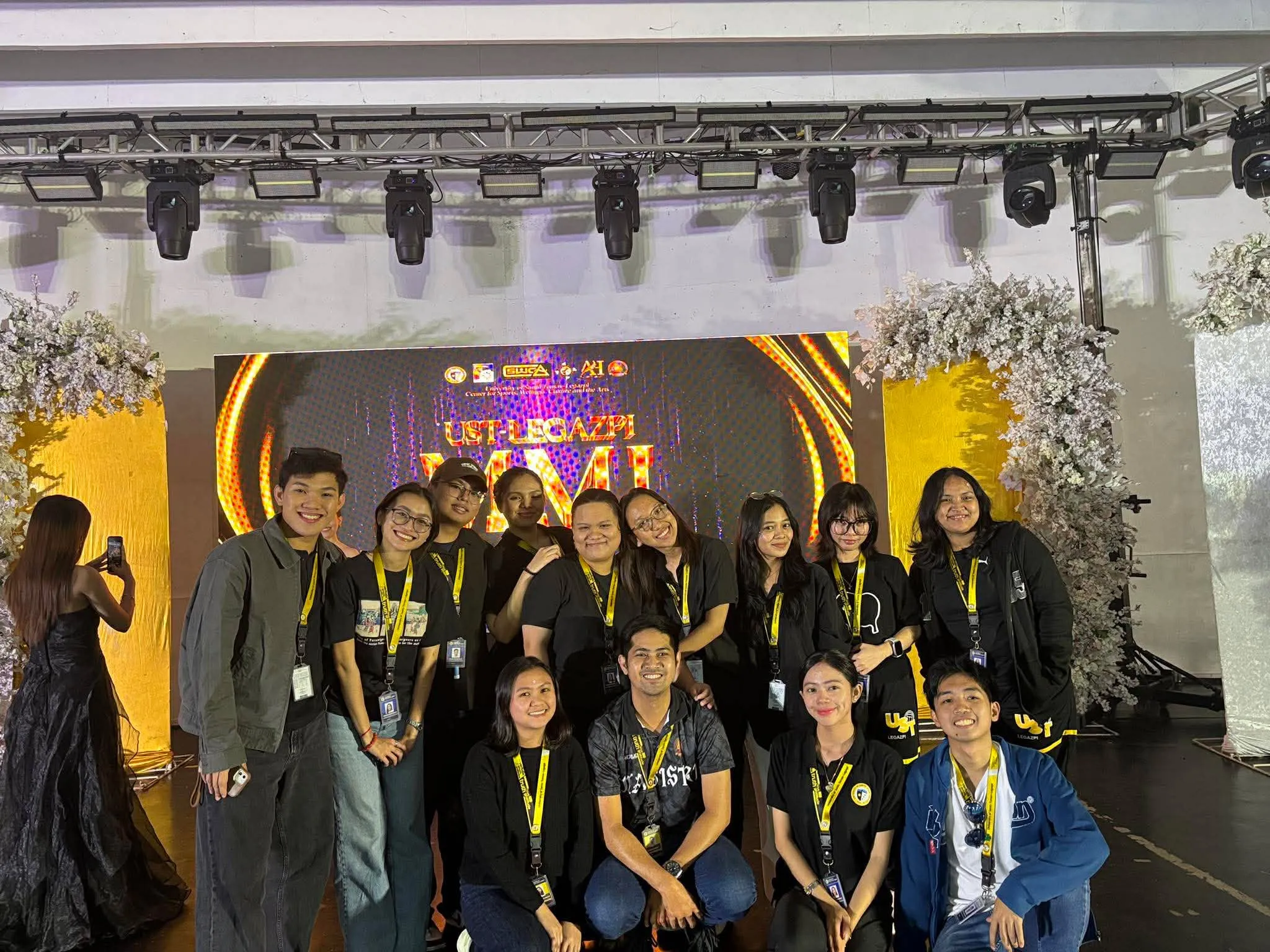 The production crew posing in front of the MMI stage backdrop, another take.