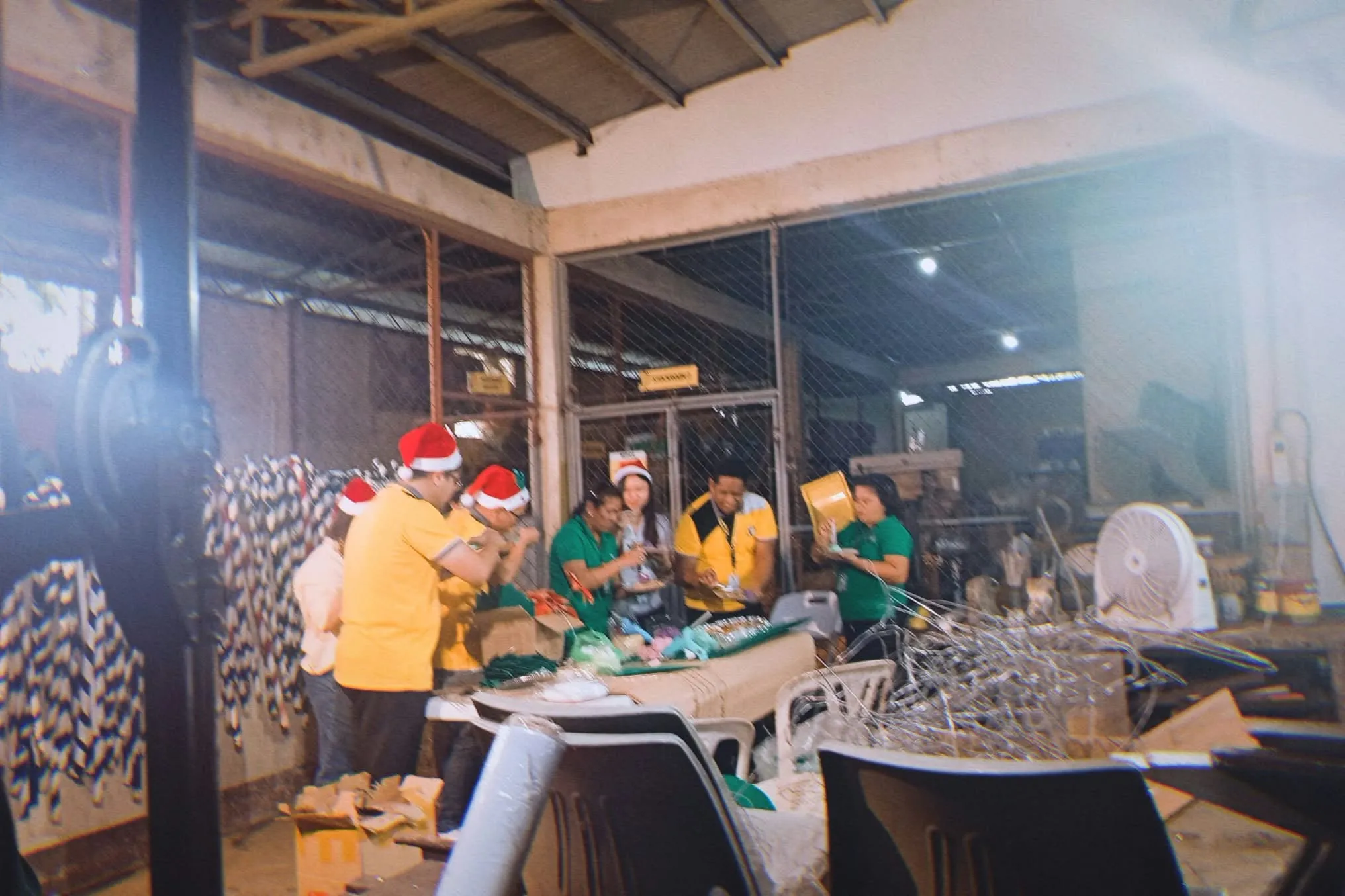 Crew in Santa hats at work around a long table.