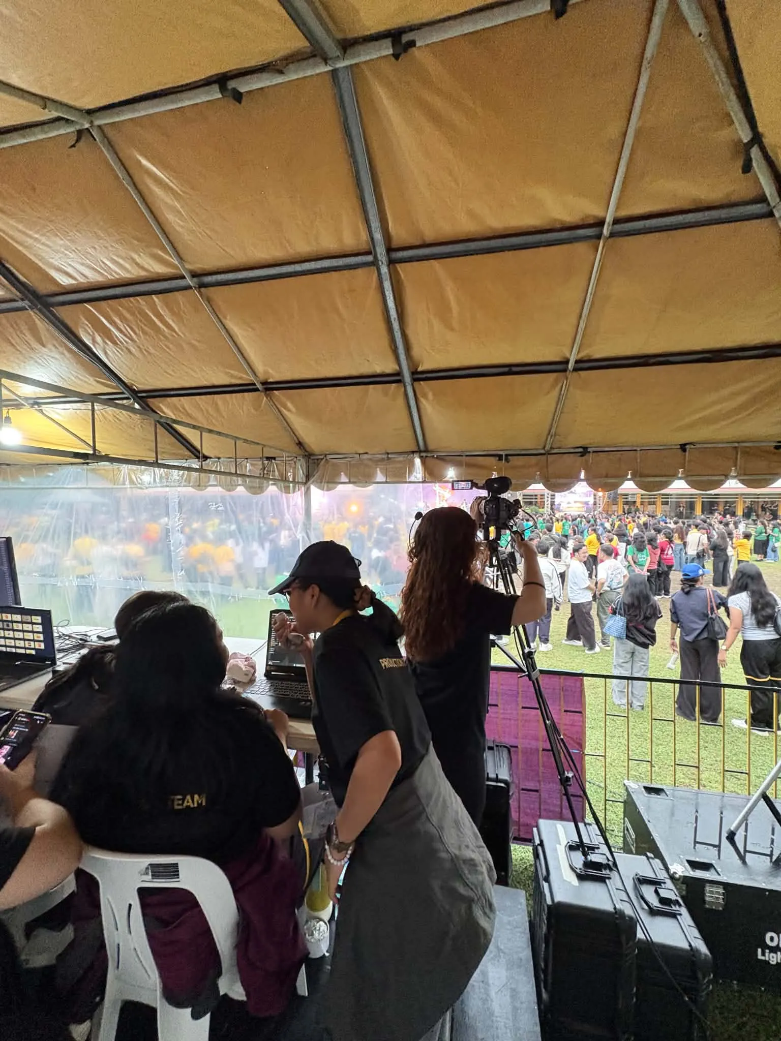 Crew filming from the production tent, the crowd beyond.
