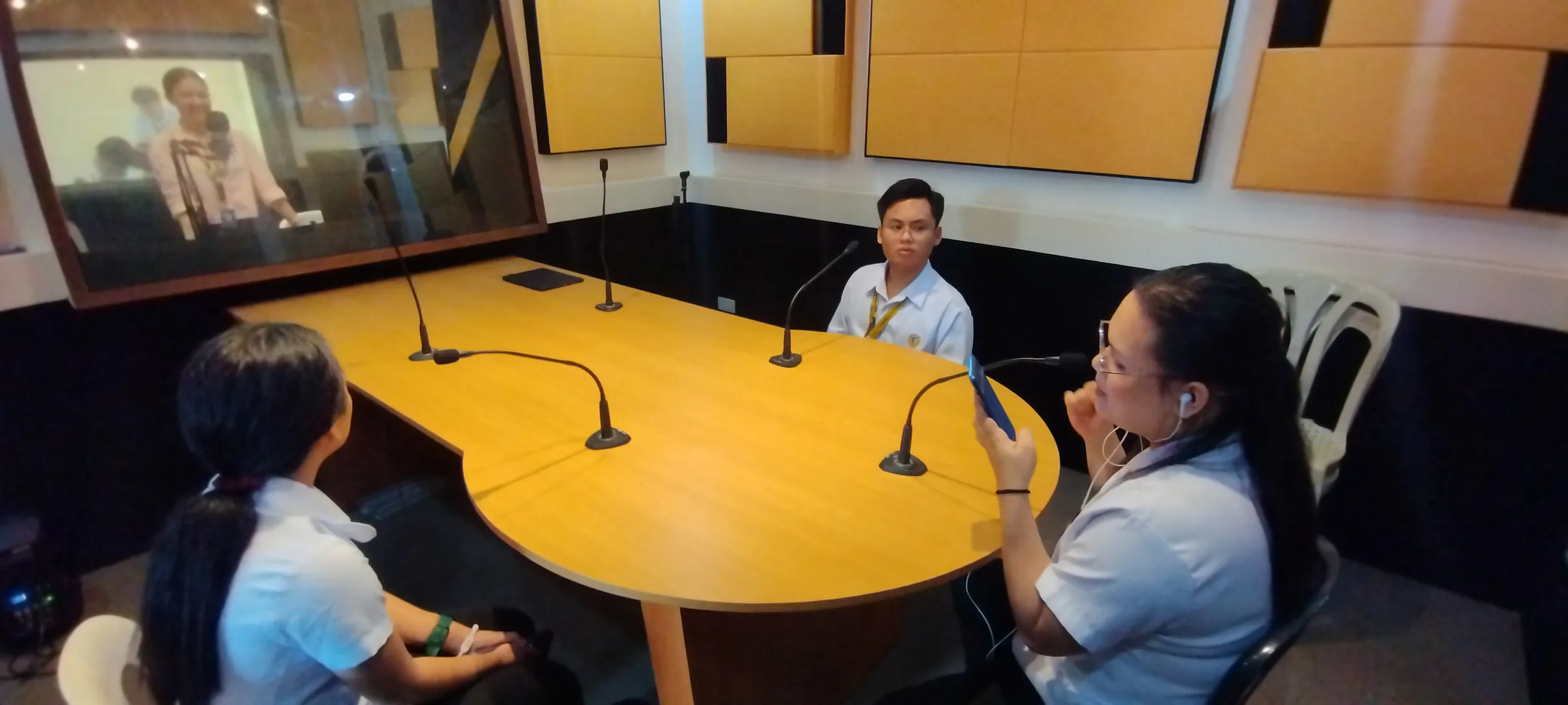 The round studio table set with microphones, a student recording.