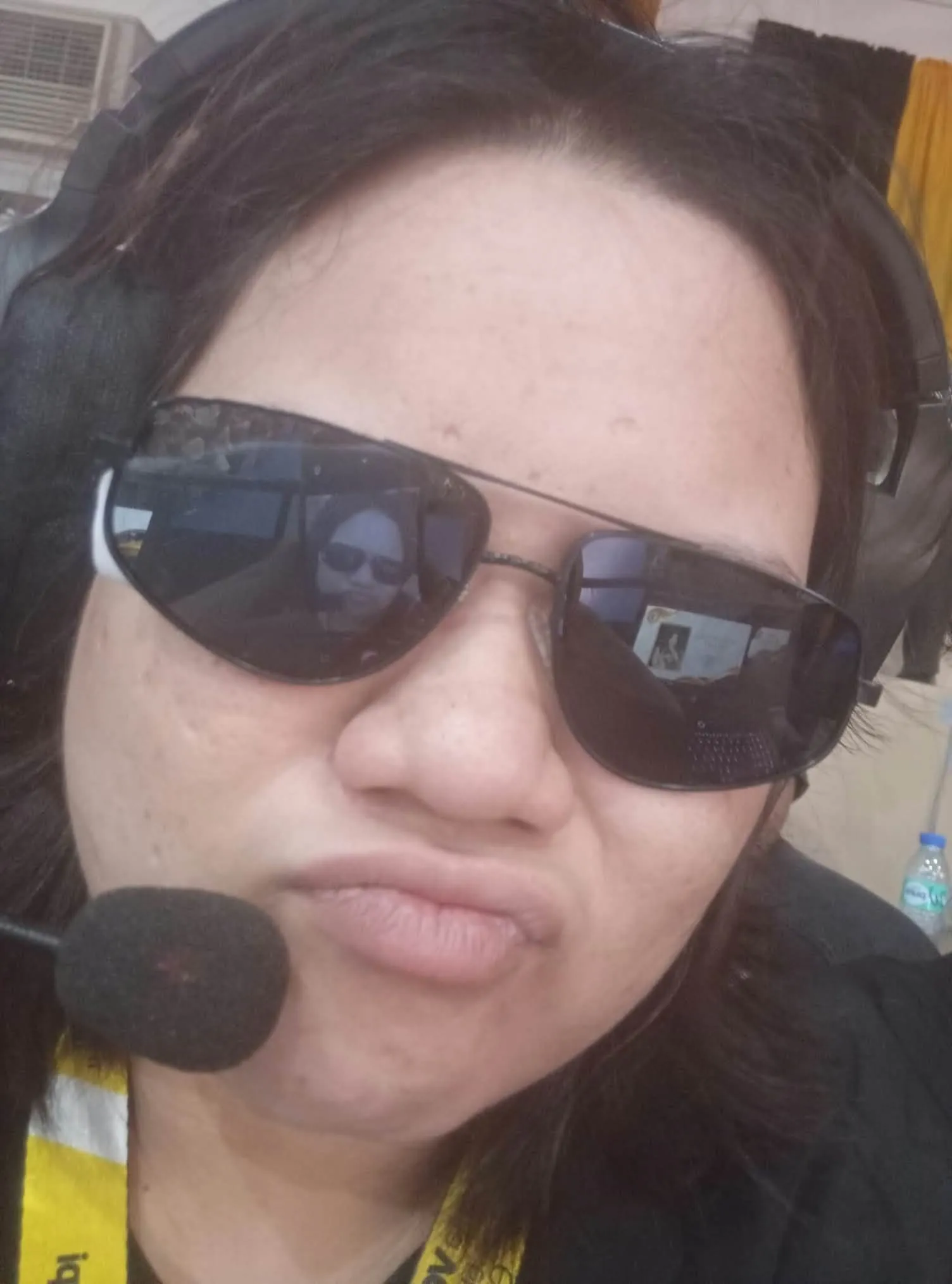A crew member in sunglasses and a headset pulling a face for the camera.